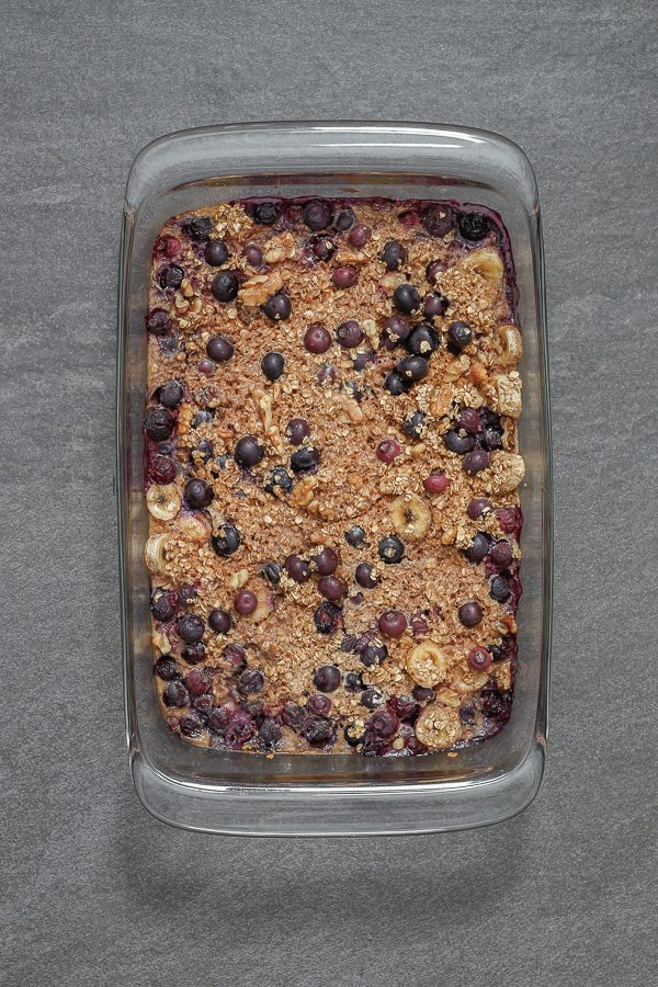 baked oatmeal including blueberries, walnuts, bananas, and oats in a container