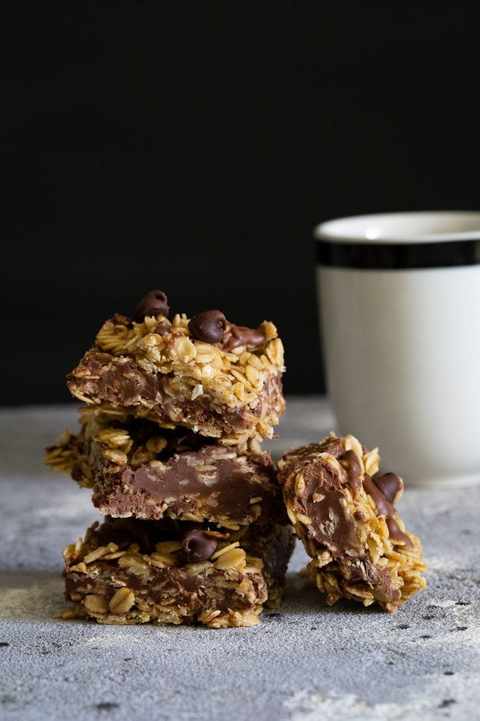stack of chocolate oatmeal peanut butter bars with a cup of coffee