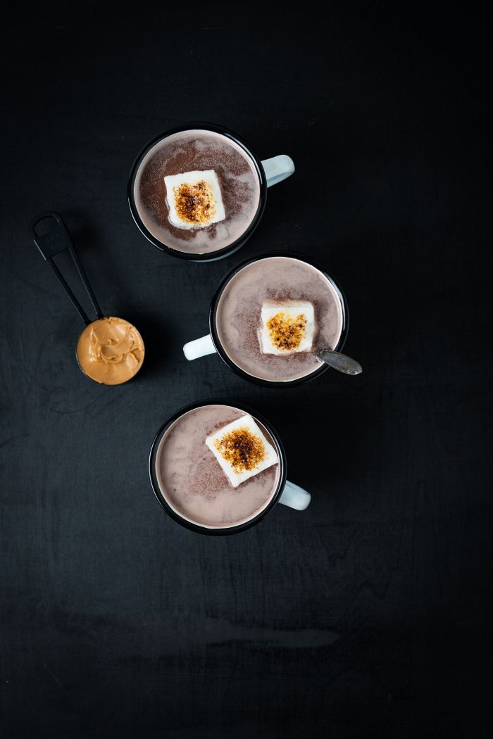 three mugs of hot chocolate in a line with toasted marshmallows on top.