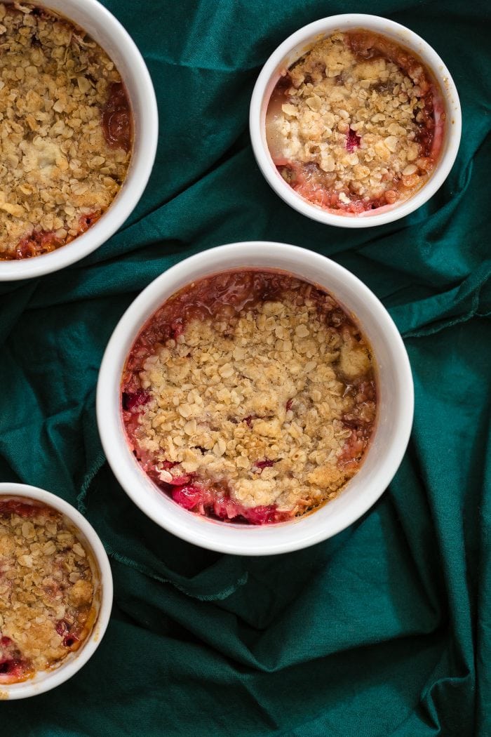 4 ramekins filled with cranberry and pear crisp topped with oats.