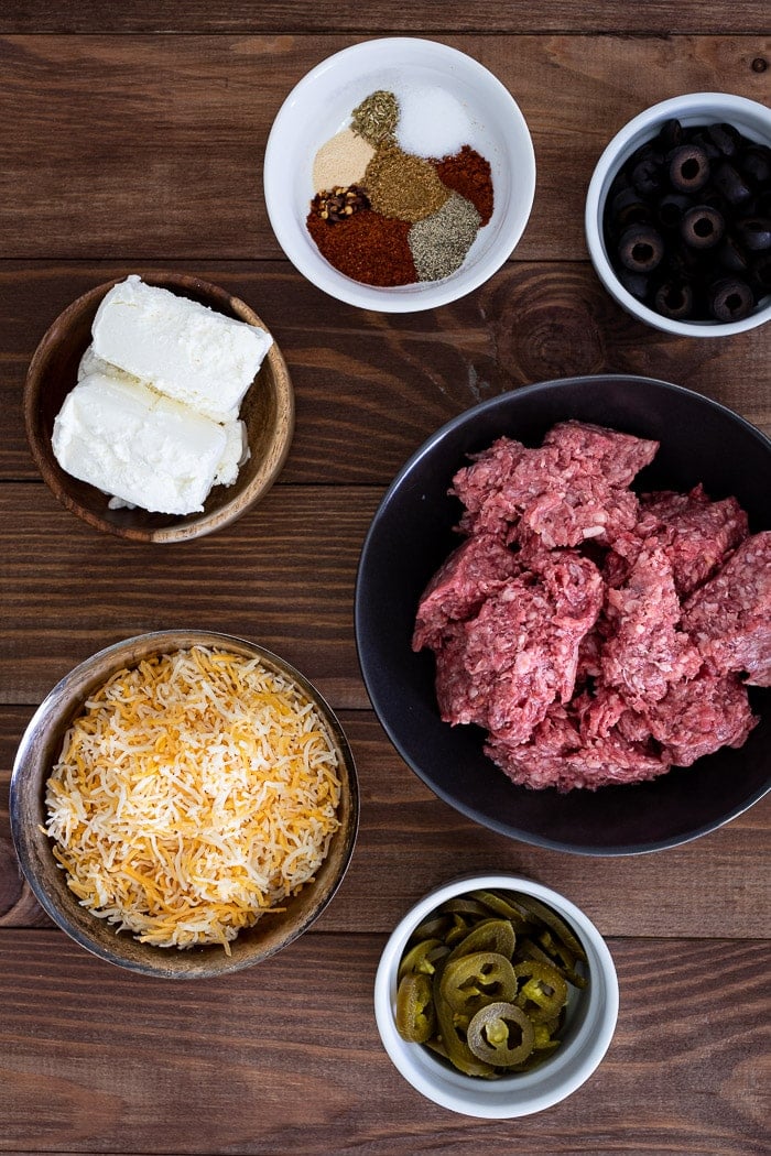 ground beef, cream cheese, shredded cheese, jalapenos, olives, and spices in various bowls