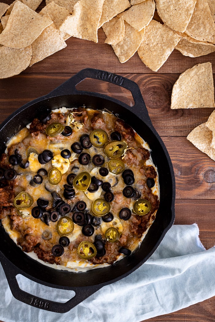 taco dip inside cast iron skillet surrounded with tortilla chips.